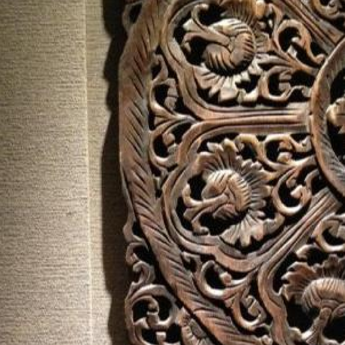 Close-up of intricately carved wooden panel with floral patterns on a textured beige background