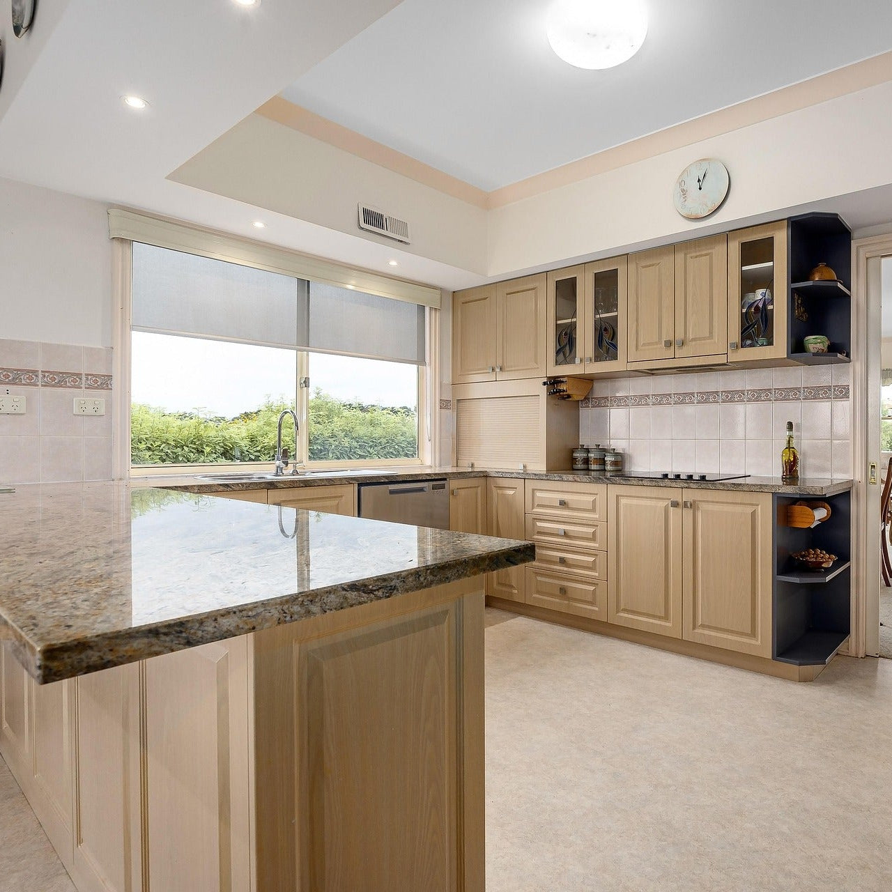 Modern kitchen with beige cabinets, marble island, and large window.